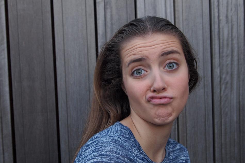 girl grimaces on the background of the fence