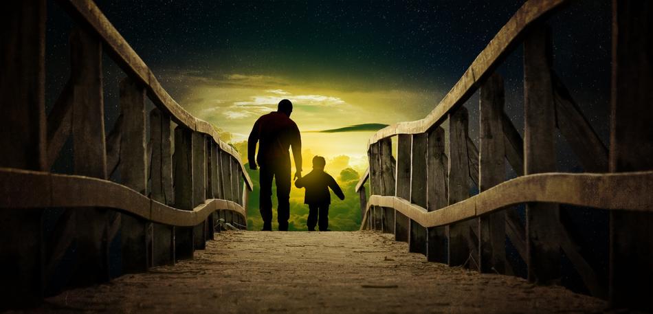 Silhouettes of the father with son on the wooden bridge at colorful sky background