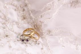 golden wedding rings lie on a wedding dress