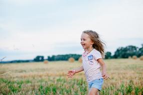 joyful girl runs on a flowering meadow