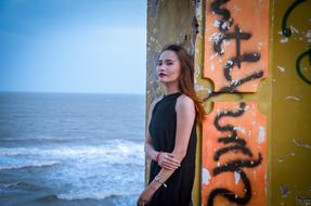 Girl on the seashore near the wall with black graffiti