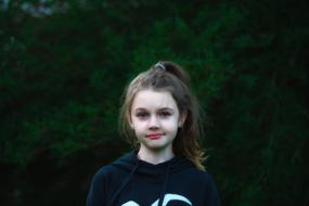 photo of a girl in a sweatshirt on a background of green tree