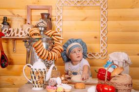 photo of a kid in a chef's hat with homemade cakes in a photo studio