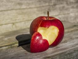 heart-shaped bitten apple close-up on blurred background