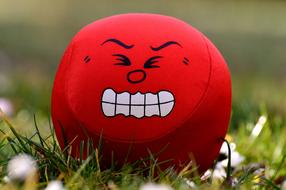 red ball with an evil face on the grass