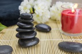 stacked black stones and red candle and flowers