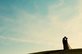 wedding couple kissing at evening sky