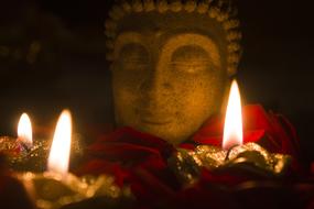burning Candles in front of stone buddha face