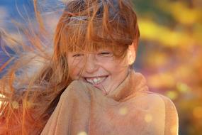 Portrait of a smiling girl, covered in a plaid, autumn