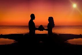 Silhouette of the couple, together, on the beach, at colorful and beautiful dawn, clipart