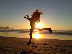 silhouette of jumping girl on the beach at sunset