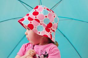 Cute, little girl with the colorful hat and turquoise umbrella