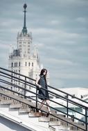 girl on the stairs against the background of the Stalinist skyscraper