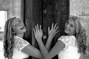 Black and white photo of the two smiling girls in dresses, posing near the architecture