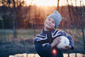 Smiling boy with the boy, near the water in beautiful and colorful sunset