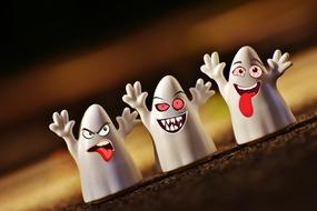 Cute white figures with Halloween faces, at blurred background