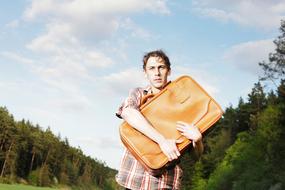 young sad Man with Suitcase at forest