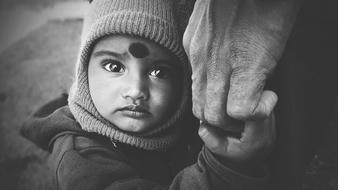 serious indian child boy holding adult manâs hand