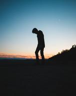 silhouette of a man on a hilltop at dusk