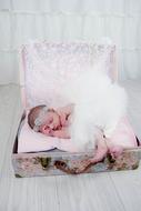 Baby girl sleeps in vintage suitcase