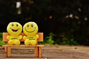 two plush emoticons on the bench