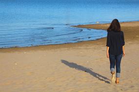 Back view of the girl, walking on the beautiful sandy beach in sunlight, in Yakutsk, Russia