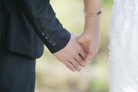 hands of the bride and groom together on a blurred background