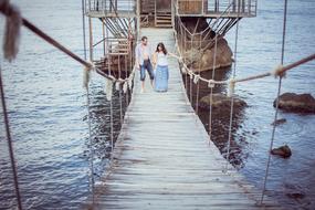 young Couple in Love walking on suspension bridge