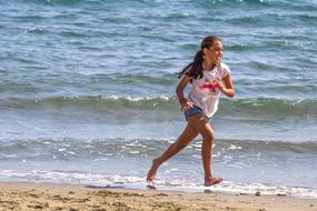 girl runs along the beach on a sunny day