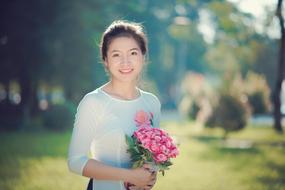 young vietnamese woman with bouquet on blurred background