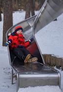 child boy on playground slide at winter