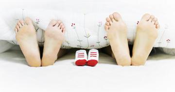 Pregnancy, bare feet of couple and baby shoes