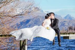 Kissing married couple in love, above the lake, at background with the mountains, on the beautiful landscape in Queenstown, New Zealand