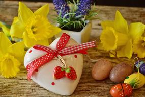 Beautiful white heart with red and white bow and yellow Daffodils and colorful Easter Gift