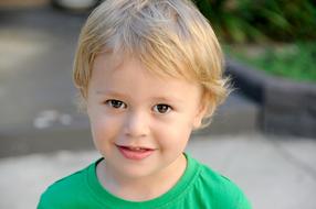 Portrait of the cute, blond child boy, in the green t-shirt
