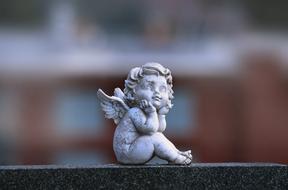 small figurine of a sad angel on a blurred background