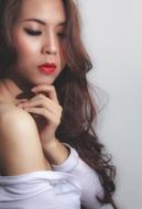 Portrait of the Asian girl with the red lips, near the white wall