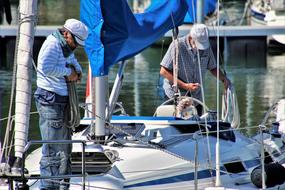 two men with ropes on boat in harbor