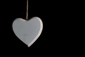 grey Heart hanging at black background