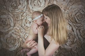 Smiling mother with the cute, laughing baby, with the white band, on the hands