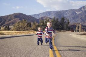 two little brothers are running down the highway