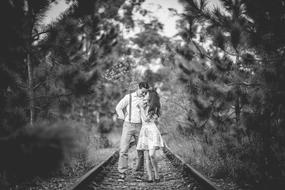 black and white photo of a couple in love on the railway