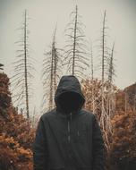 person in hoodie in front of dry forest at fall