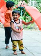 two asian child boys playing with red umbrellas