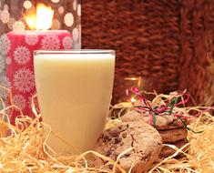 Beautiful glass of milk, near the beautiful, burning, red candle, among the beautiful cookies