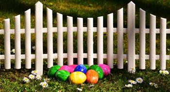 colorful easter eggs near white fence in the garden