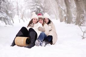 Smiling woman on the toboggan, among the beautiful, snowy forest