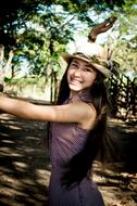 smiling girl with hat under a tree