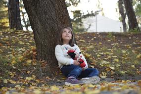 little girl sitting near a tree