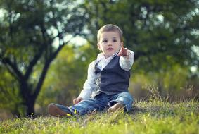 Happy Child Boy sits on grass in park